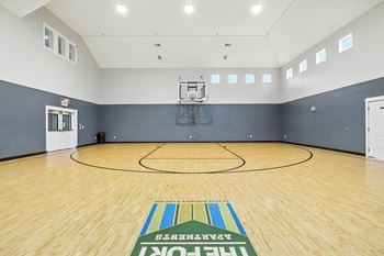 A basketball court with a wooden floor and a basketball hoop.